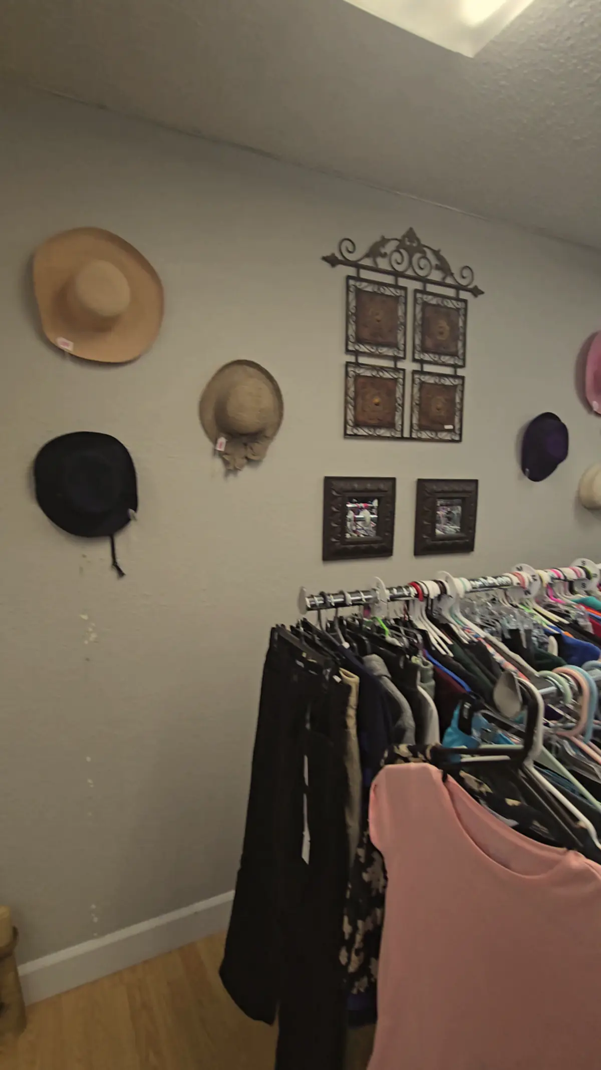 A hallway of clothing racks and hats on the wall